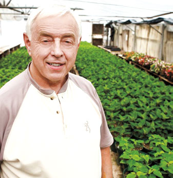 Dave Gibby in a greenhouse with rows of plants