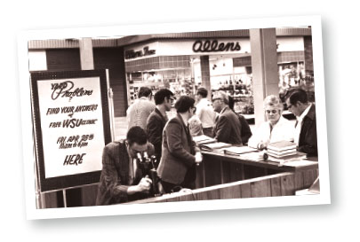 Black and white photo of people at a booth getting gardening advice