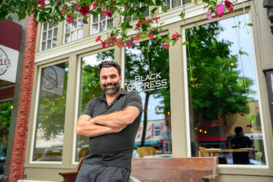Nick Pitsilionis stands in front of window at Black Cypress restaurant