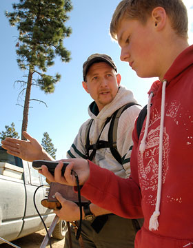 Ben Maletzke helps student DJ Landes interpret the signal from a GPS (Global Positioning System) unit. The signal, from the collar worn by a female cougar, tells them where the cougar's den is. Six times a day, the GPS transmitter sends data on the cougar's location to a satellite. The researchers can download the data at any time. When the GPS information shows that a female cougar has stayed put for longer than a few days, it usually means she has denned up to give birth.