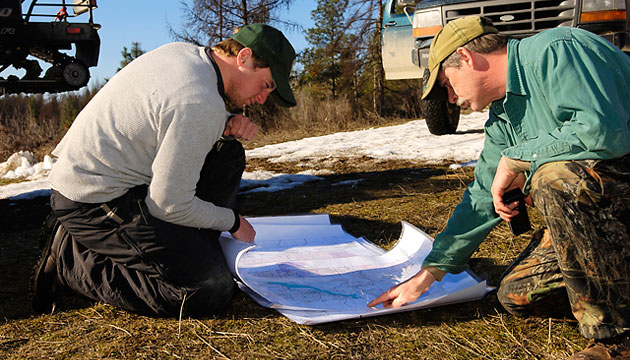 Getting a clear signal is just the beginning of the search. The cat may be in a canyon, across an unfordable stream, or deep within a roadless area. Here, Wilson and houndsman Tom MacArthur study a map to figure out the best route to reach a cougar they've located via GPS (Global Positioning System) signal.