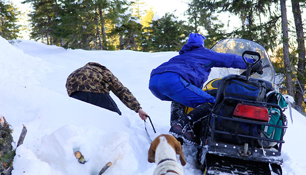 Wilson pulls the snowmobile while Cooley steers it along the edge of a steep drop-off.