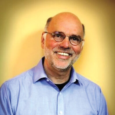 Profile of Bob Appleyard in a blue shirt with yellow background