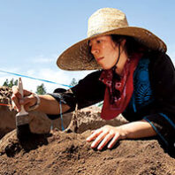 A woman in a hat digs for artifacts