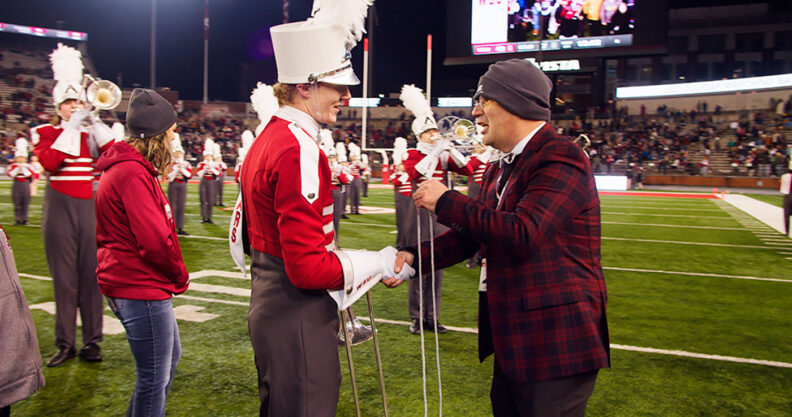WSU band director Jon Sweet on the football field talks to a Cougar Marching Band member