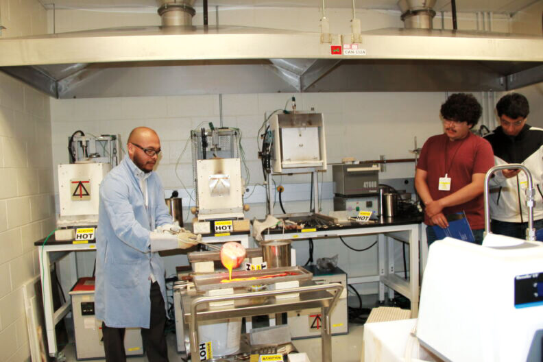 José Marcial in a lab pours out a molten substance as two people watch