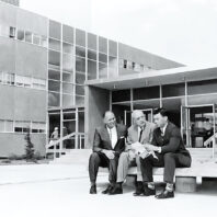 Black and white photo of three men in front of Johnson Hall at Washington State University