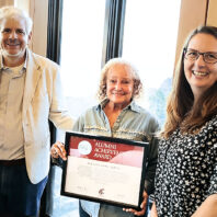 Laurelle Danton holds up WSU Alumni Achievement Award between two people