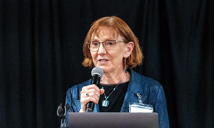 Dawn DeWitt speaking into a microphone at a presentation