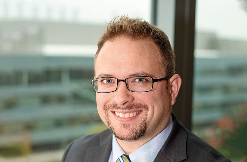 Head shot of Sterling McPherson in front of a window overlooking the WSU Spokane campuse