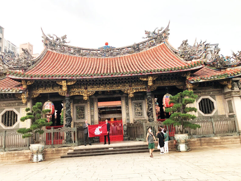 Jeff Holy holds up the WSU Cougar flag in front of Lungshan Temple in Taipei
