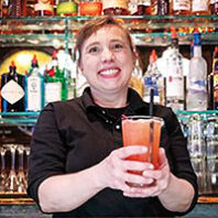 Tawny Szumlas holds a cocktail behind the bar