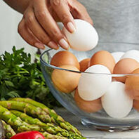 hand picking up eggs from a glass bowl
