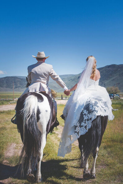 Man and woman on horseback in wedding clothes