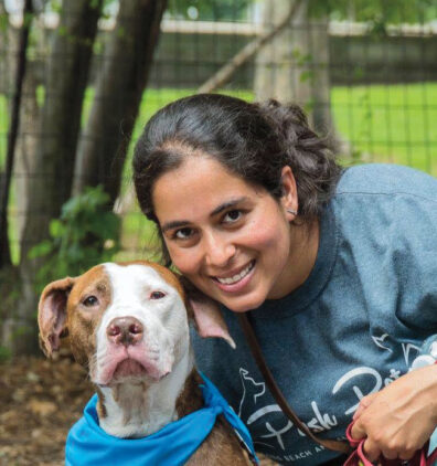 Smiling woman net to her dog wearing a blue kerchief