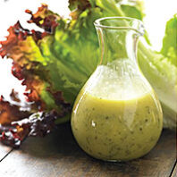 bottle of mustard salad dressing with red leaf lettuce behind it