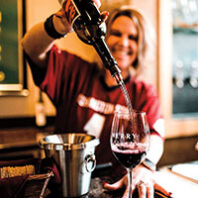 Woman pouring red wine into a glass