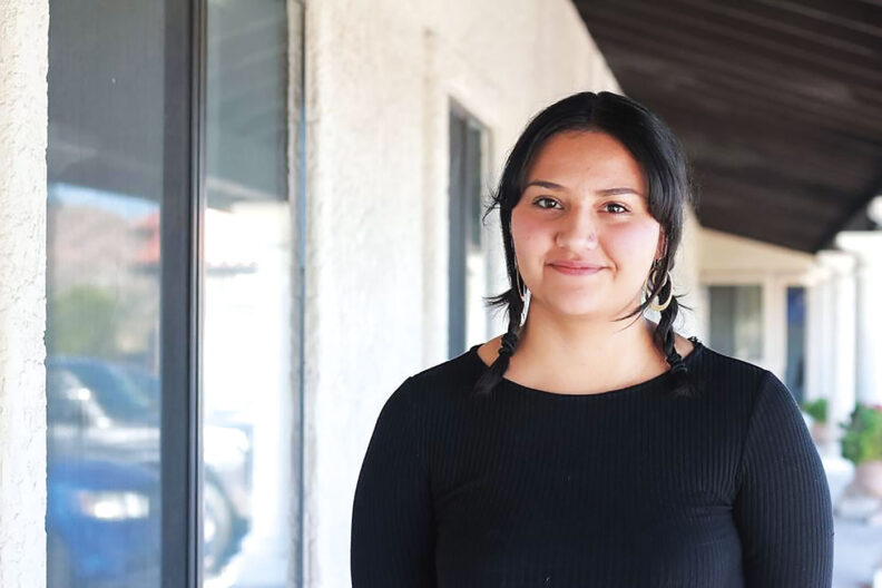 Closeup of Daisy Zavala Magaña next to a white stucco building