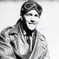 Black and white photo of aviator Clyde Pangborn in leather jacket with helmet and goggles