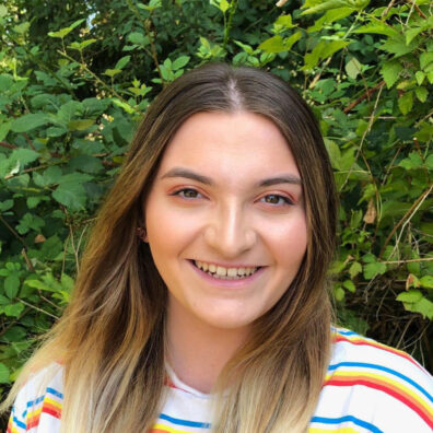 Closeup of smiling young woman in front of trees