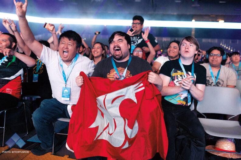 Crowd of yelling audience with a man in front with a WSU logo flag