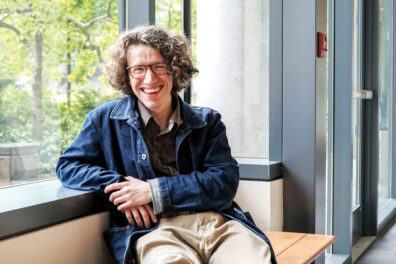 Young man Questen Inghram with glasses sits by a window