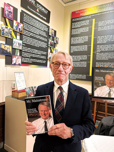 John C. Hughes with copy of Mr. Mainstream, the book he wrote about Sam Reed