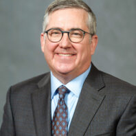 Profile of older man with graying hair in glasses, suit and tie