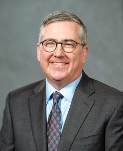 Profile of older man with graying hair in glasses, suit and tie