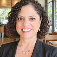 Closeup of a smiling middle-aged woman with curly dark hair in a business suit
