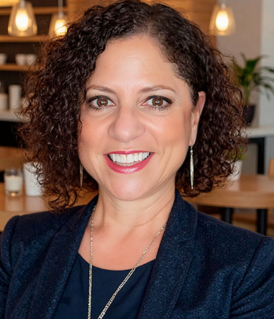 Closeup of a smiling middle-aged woman with curly dark hair in a business suit