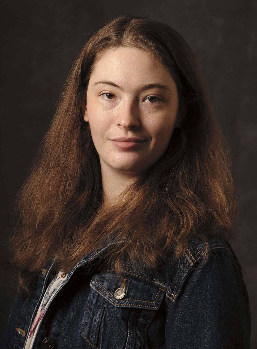 Headshot of a smiling young woman with long brown hair