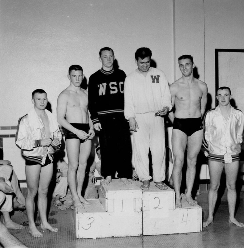 Black and white photo of swimmers on a podium after a swim meet