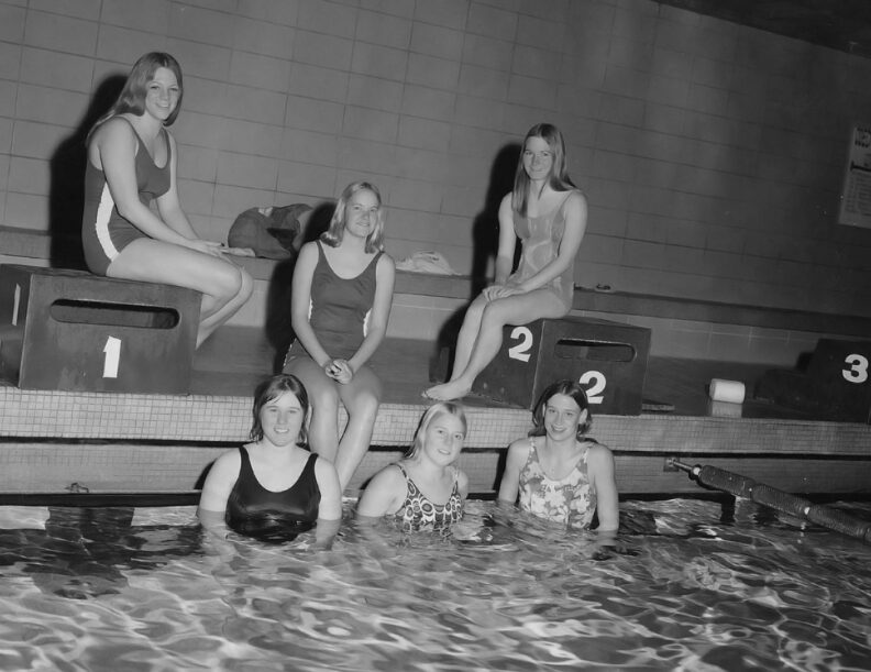 Black and white photo of six women swimmers in swimsuits by a pool