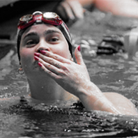 Woman swimmer in a pool blows a kiss after a win
