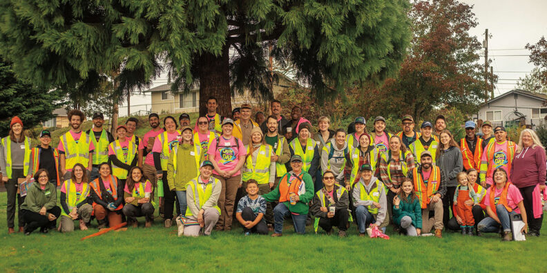 Large group of people in city park wearing brightly colored safety vests