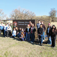 A WSU history class members in front of the Whitman Mission National Historic Site sign in Walla Walla
