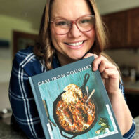 Chef Megan Keno smiles and holds up her book Cast Iron Gourmet