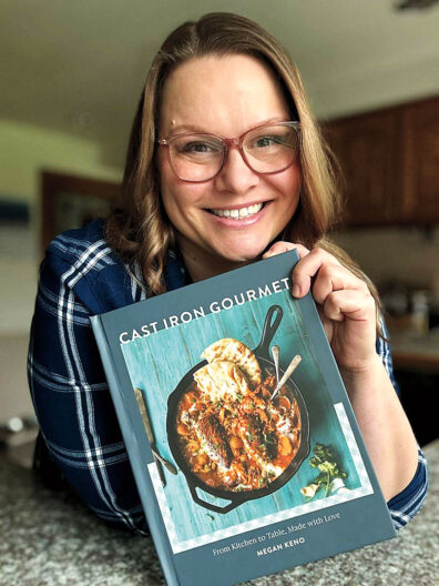 Chef Megan Keno smiles and holds up her book Cast Iron Gourmet