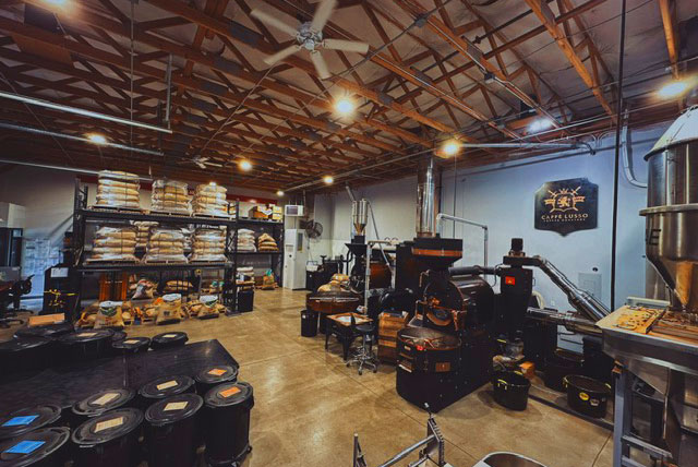 large room with coffee roasting equipment, bags and bins of coffee