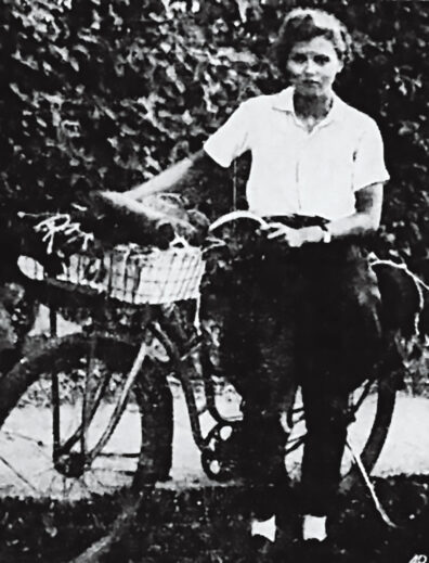 Black and white photo of a young woman with a bicycle in the 1930s