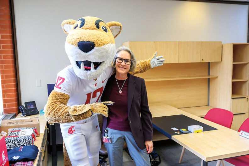 WSU President Elizabeth Cantwell smiles while posing next to WSU mascot, Butch Cougar, during a video shoot.
