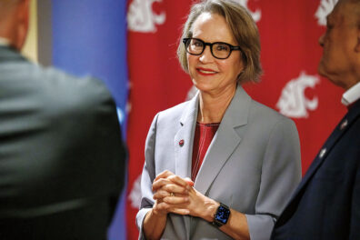 Dr. Elizabeth Cantwell, smiling, with a WSU logo background, stands next to WSU Regent Enrique Cerna.