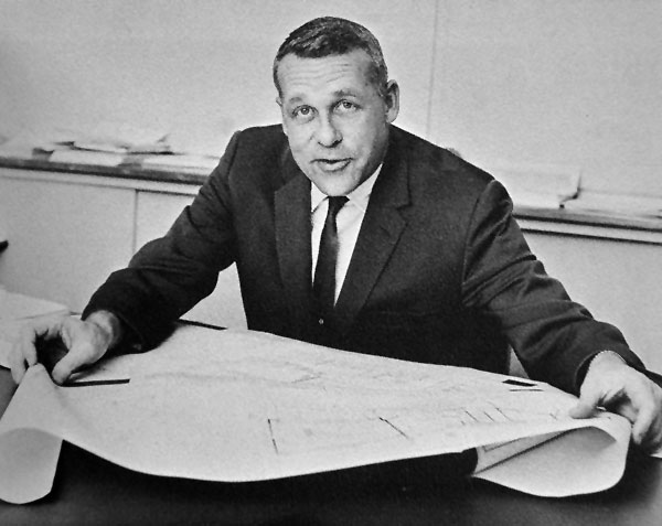 Black and white photo of WSU journalism professor Bob Mott in a suit reading a newspaper