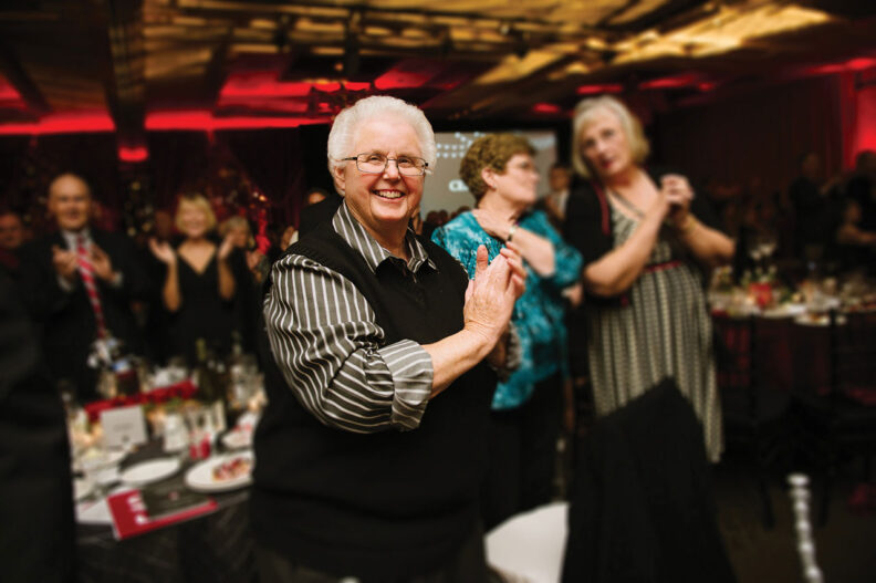 Gay Selby smiling, clapping at an event