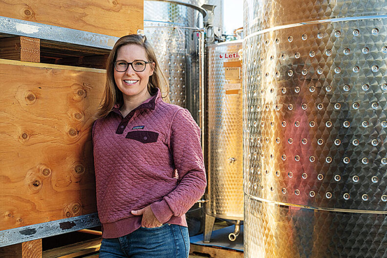 Allison McMahon in front of winemaking equipment