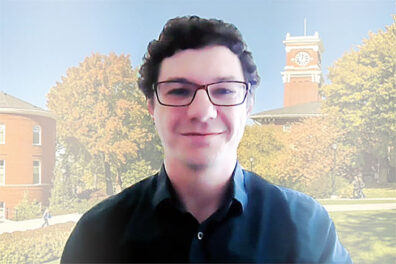 Head shot of Jordan Foley with dark dress shirt and background of WSU campus