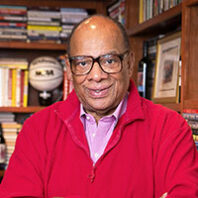 George Raveling in glasses, a red sweater and a dress shirt