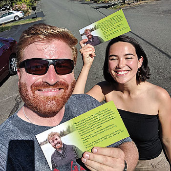 Kevin Schilling holds a campaign flyer. Young woman stands behind him with same flyer.