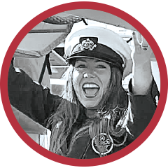 Circular black-and-white portrait of a woman wearing a peaked cap, framed by a red border